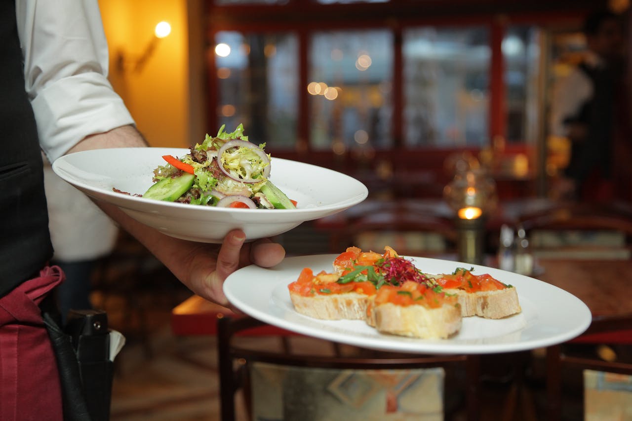 Crafting Captivating Headlines: Your awesome post title goes here A waiter serves a fresh salad and hors d'oeuvres in a cozy restaurant setting.