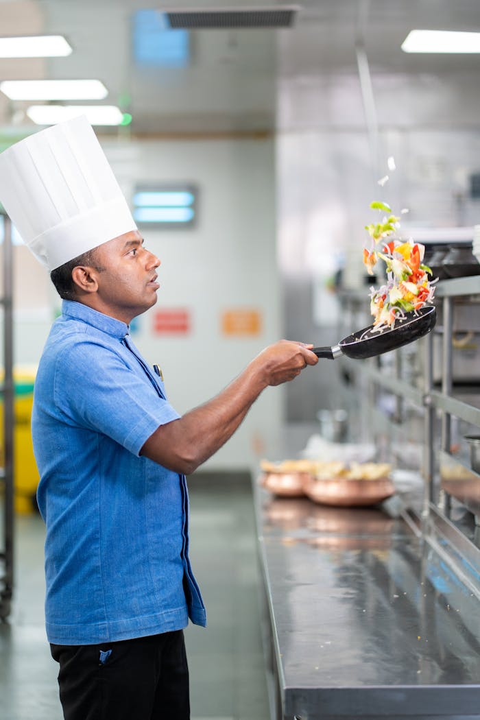 Skilled chef in a blue shirt expertly tosses vibrant vegetables in a modern kitchen.