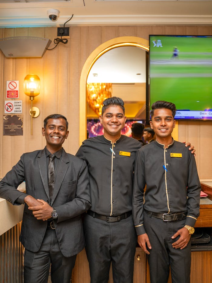 Three well-dressed staff members posing in a luxurious casino interior in Goa, India.